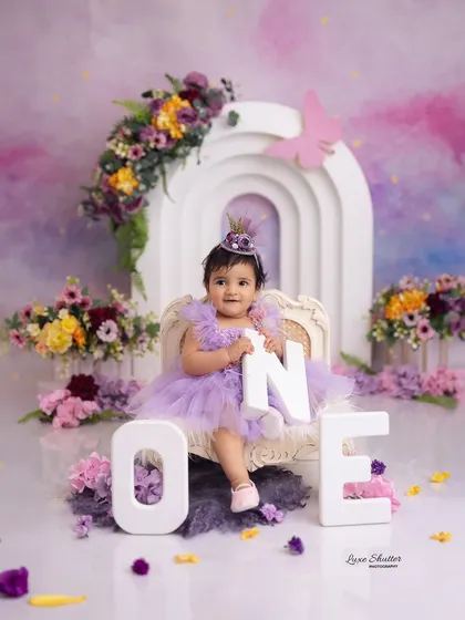 A magical first birthday portrait with a rainbow arch and a pastel sky backdrop, creating a dreamy and colorful celebration.