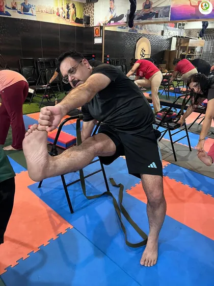This student is using a chair and belt to work on a standing leg stretch. This is a fantastic way to improve hamstring flexibility while maintaining balance and stability.