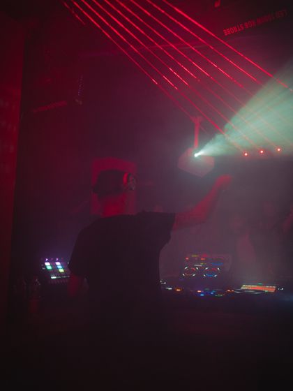 From behind the console, surrounded by red lights and smoke. This is my element, shaping the sound and guiding the energy of the dance floor through the night.