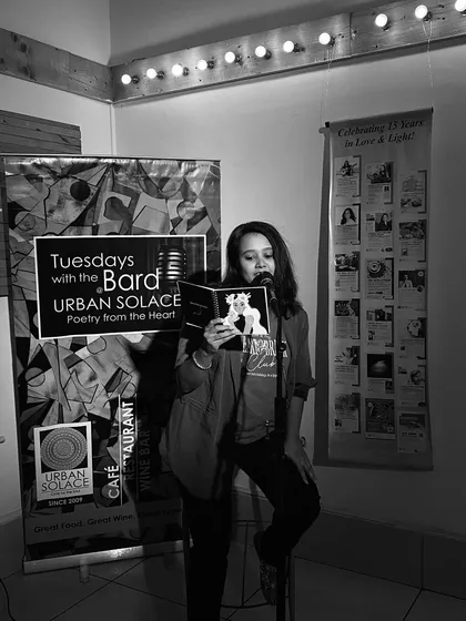 A black and white shot of a poet reading from her book, lost in the world of her own words. These are the moments of pure connection we cherish.