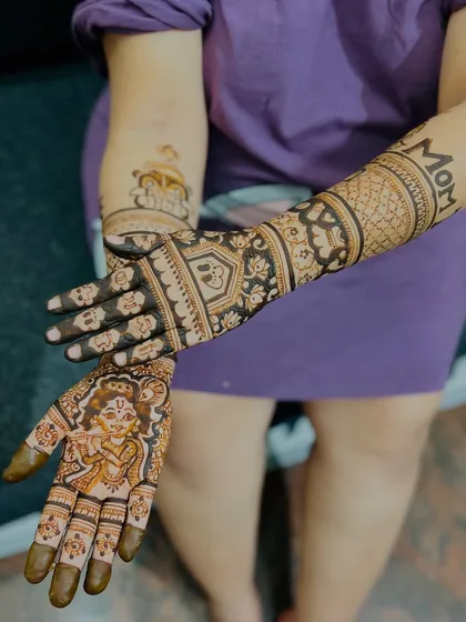 I love creating personalized mehendi for baby showers. This design features a portrait of baby Krishna on one palm and the word "MOM" on the forearm, celebrating the journey into motherhood with unique and meaningful art.