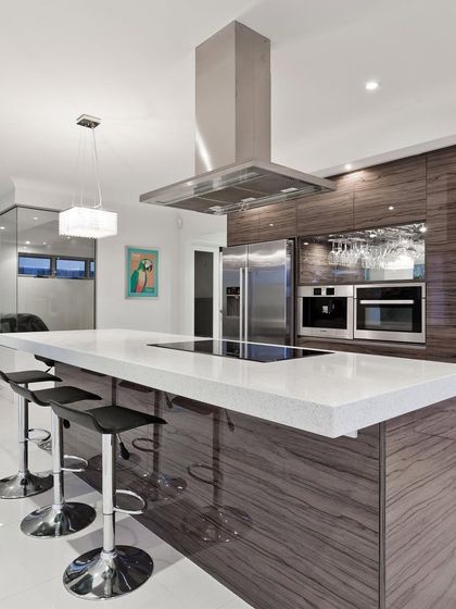 An example of an open-concept kitchen with a large island that doubles as a breakfast bar. The dark wood-grain cabinets and white waterfall countertop create a striking contrast, perfect for contemporary homes.