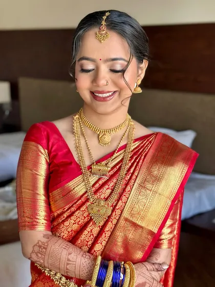 A beautiful smiling portrait. The makeup enhances her happy glow, with a classic red lip that perfectly complements her traditional attire.