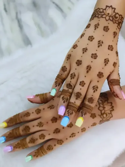 A beautiful example of modern, minimalist henna. This scattered pattern of tiny roses and leaves creates a delicate, jewelry-like effect on the hands. It's a chic and subtle choice for any guest or family member.