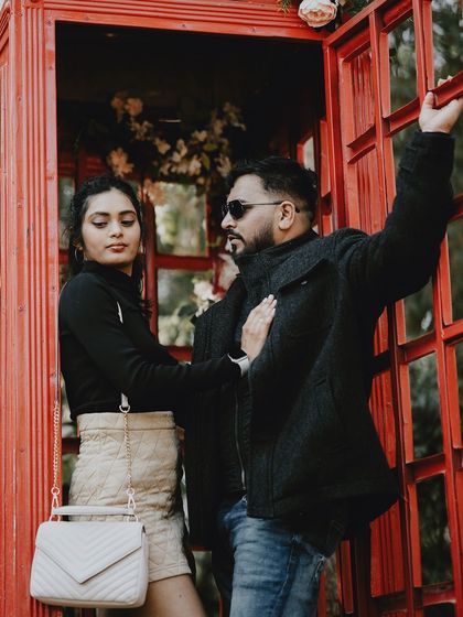 A dramatic and stylish pose in a red telephone booth, capturing a high-fashion, editorial look.