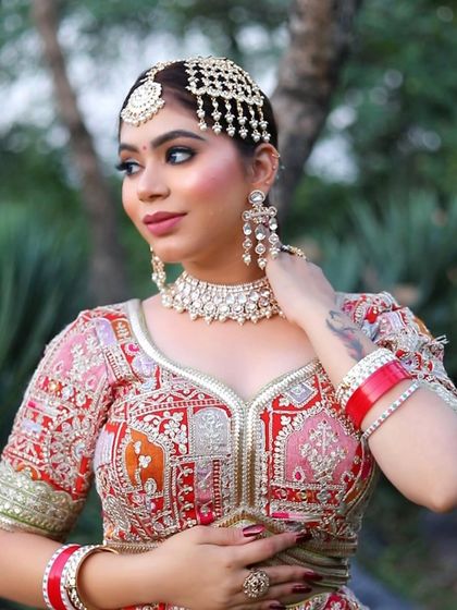 A modern take on the traditional bridal look, featuring a Pakistani-style paasa. The makeup includes a sharp, winged liner and a blue-toned eyeshadow to complement the intricate outfit embroidery.