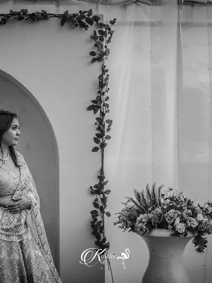 A black and white shot of a couple holding hands, framed by an archway, creating a sense of quiet intimacy.