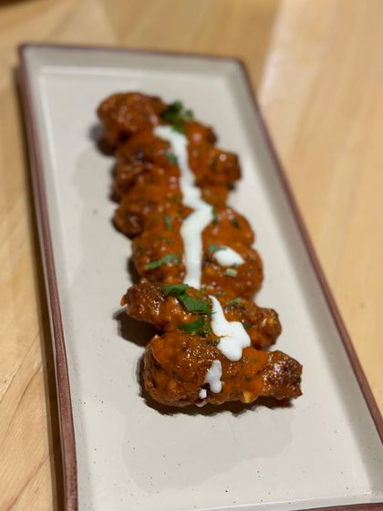 Our spicy chicken wings are a crowd favorite. Tossed in a tangy sauce and drizzled with cream, they are the perfect appetizer to share with friends.