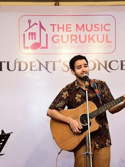 An adult student performs with his acoustic guitar at the TMG Student's Concert. Our community includes learners of all ages, all sharing a passion for music.