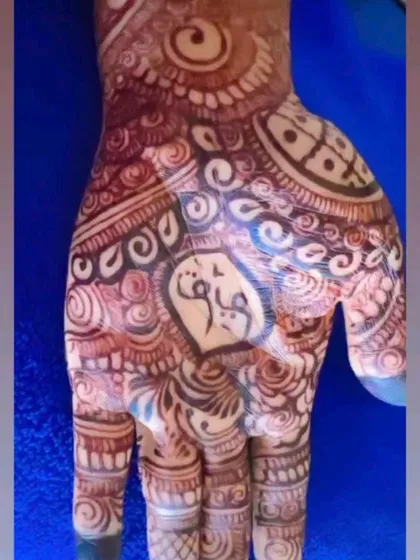 A close-up of a name written in Arabic script, nestled within a heart in the center of the palm. This is a beautiful way to honor your partner in your bridal henna.