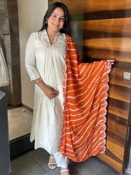 An off-white chanderi viscose kurta paired with a bright orange leheriya dupatta. It's a classic combination that's perfect for celebrating any festival.