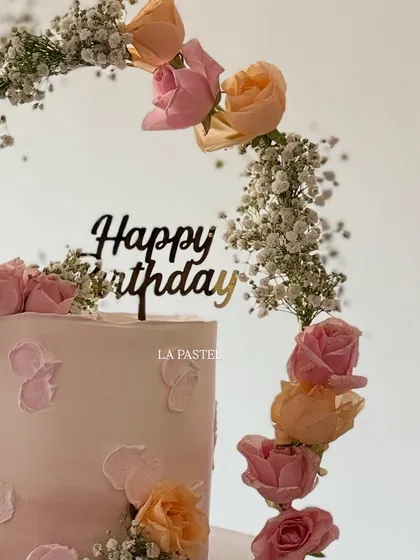 A close-up on the 'Happy Birthday' topper and the beautiful fresh flowers on this elegant cake.