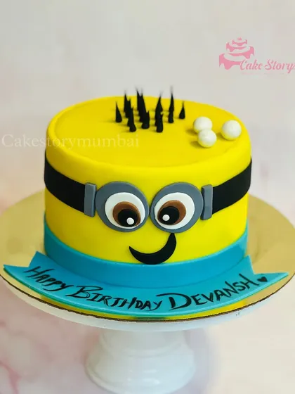 A fun and simple Minion-themed cake. The bright yellow cake is designed to look just like a cheerful Minion, complete with his goggle and smile.