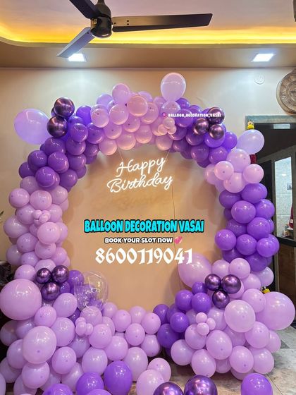 A full ring of purple balloons for a birthday celebration. The two-tone purple design with a neon sign is simple yet very effective.
