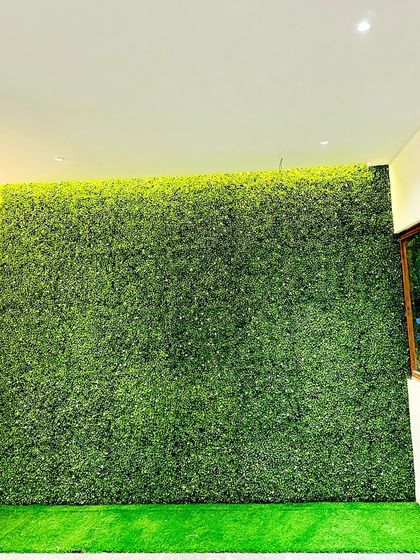 This indoor green wall is paired with an artificial grass border on the floor, creating a seamless transition and enhancing the feeling of a complete garden space inside the home.