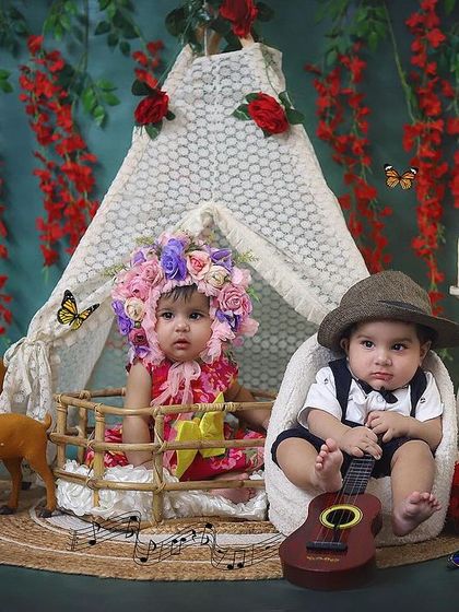 A whimsical woodland themed portrait featuring twin babies with their family. One baby is dressed as a little musician while the other wears a floral crown, showing their unique personalities even as newborns.