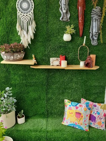 Another angle of the grass-covered balcony, showing the built-in seating nook with colourful cushions. The floating pinewood shelves provide a perfect spot for displaying decor items like candles and planters.