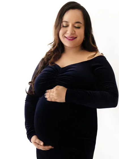 A quiet and tender solo portrait of a mom-to-be in a classic navy blue velvet gown, cradling her baby bump.