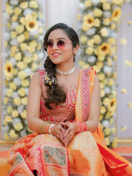 A full view of the bride's Haldi look, sitting against a backdrop of sunflowers, looking absolutely radiant.