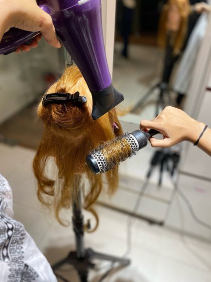 Another angle of a student perfecting their blow-dry technique, focusing on directing the airflow to create a smooth, polished finish.
