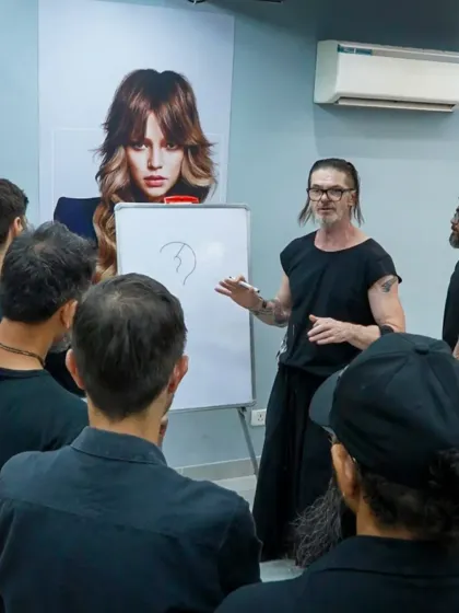 Education at our academy goes beyond practical work. Here, Bill Watson uses a whiteboard to break down the theory behind a haircut, ensuring our students grasp the foundational principles of structure and shape.