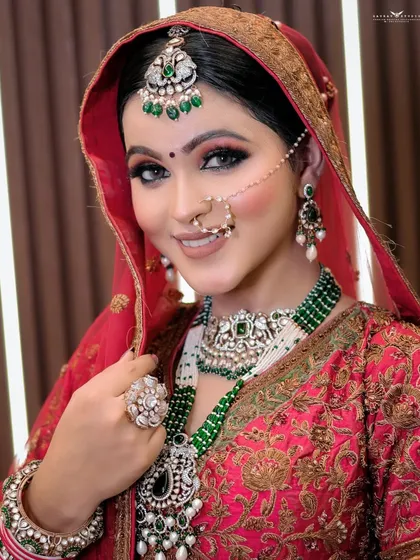 A classic bridal portrait showcasing the green-beaded jewelry contrasting with the red lehenga.
