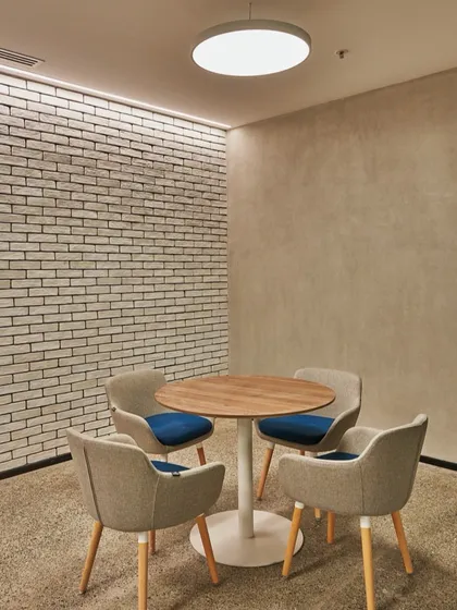 A small, quiet meeting nook with a white brick wall and comfortable upholstered chairs. This space provides a calm retreat for focused conversation.