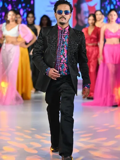 Taking the final walk on the runway with my collection. This moment captures the energy of a fashion show, where I present my latest designs, including this custom-beaded black jacket and floral shirt.