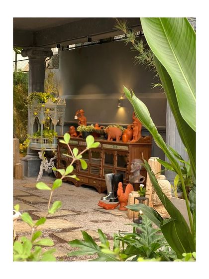 A glimpse into the eclectic and art-filled landscape designed for Peacock Life in Hyderabad. The space features a mix of antique furniture, colorful sculptures, and diverse planters.