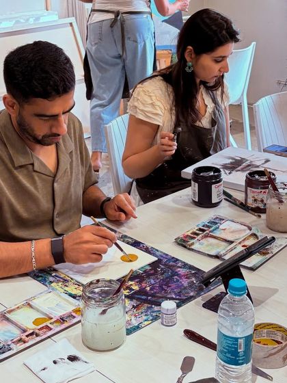 A quiet moment of focus. This image captures two participants deeply engaged in their painting, with all the necessary supplies right at their fingertips.