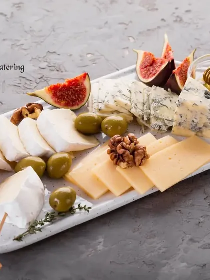 A refined cheese platter featuring creamy brie, tangy blue cheese, and mild gouda, perfectly complemented by fresh figs, walnuts, and olives. A simple yet elegant offering.