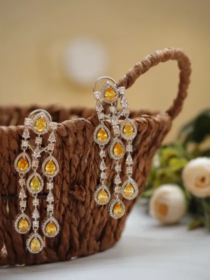 Nestled in a rustic wicker basket, these yellow gemstone chandelier earrings create a beautiful contrast between natural textures and refined sparkle. The soft, out-of-focus background keeps the focus on the intricate details.