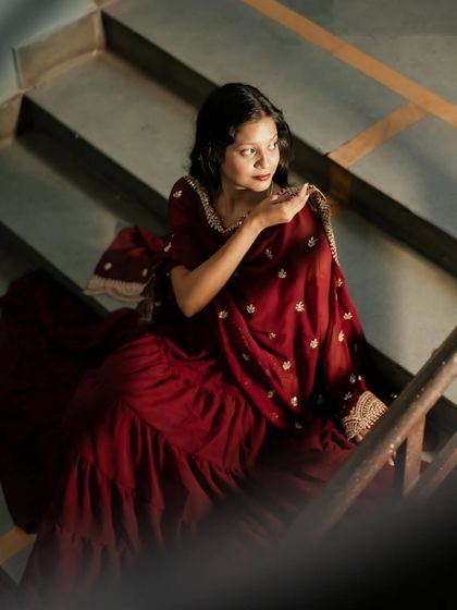A seated portrait that uses the shadows of the staircase to create a moody and intimate feel, highlighting the rich texture of the dress.