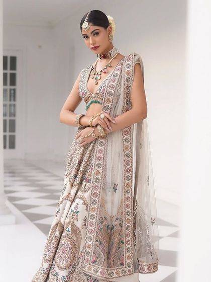 The bride's pose highlights the intricate border of the dupatta and the beautiful flare of the skirt.