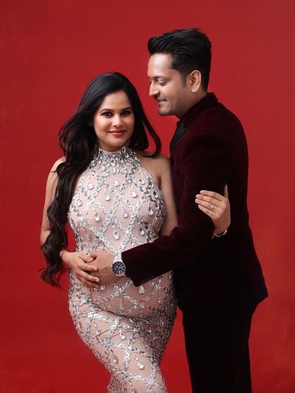 A glamorous couple's portrait against a bold red backdrop. The sparkling silver gown and deep red suit create a look of pure Hollywood elegance and drama.