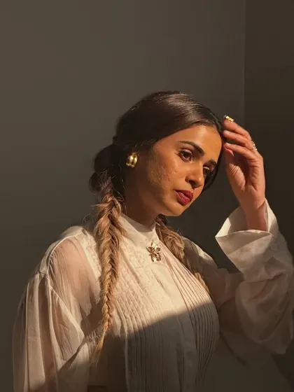 A beautiful behind-the-scenes moment with Shalmali Kholgade. This shot captures the soft, romantic makeup with a berry lip stain and fishtail braids, highlighted by the golden hour light.