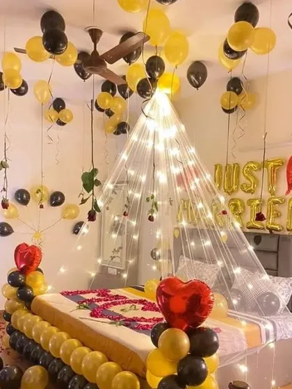 A 'Just Married' first night bedroom decoration with a canopy of fairy lights and black and yellow balloons.