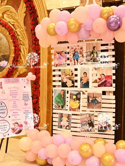 A personalized photo display for a butterfly and fairy-themed first birthday. A milestone board and a photo grid are set up with pastel balloon accents, creating a sweet corner to reminisce.
