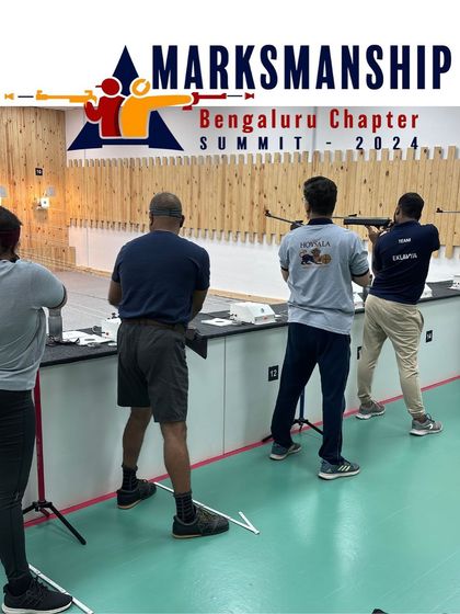 Competitors in the Open Sight Rifle event at the Marksmanship Summit. This view from behind the firing line shows the focused stances of the shooters as they aim at the targets.