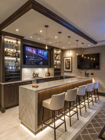 A concept image of a luxurious home bar, complete with a marble counter, back-lit shelving, and comfortable bar stools. We can design a similar entertainment space for your home.