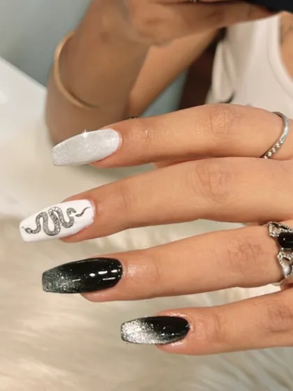 An edgy and cool design featuring black and white nails with a silver snake accent. The glittery texture of the snake makes it pop.