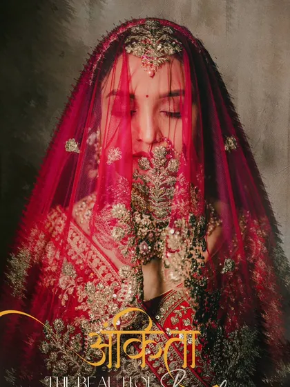 An artistic portrait of the bride with her face partially covered by her embroidered red veil, creating a sense of mystery and tradition.