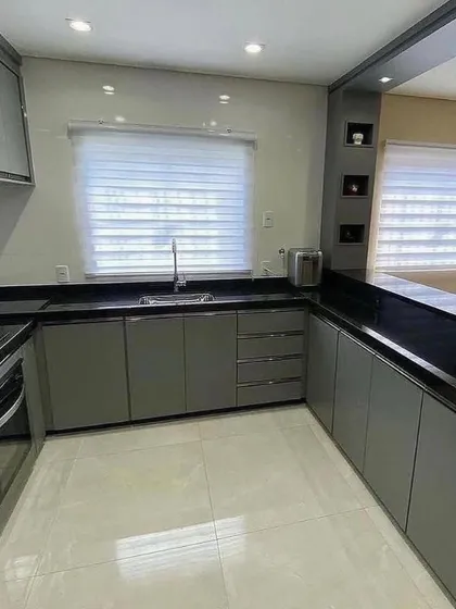 A full view of the U-shaped kitchen layout, showing the efficient use of space with the breakfast bar. The combination of grey cabinets and black countertops is both practical and stylish.