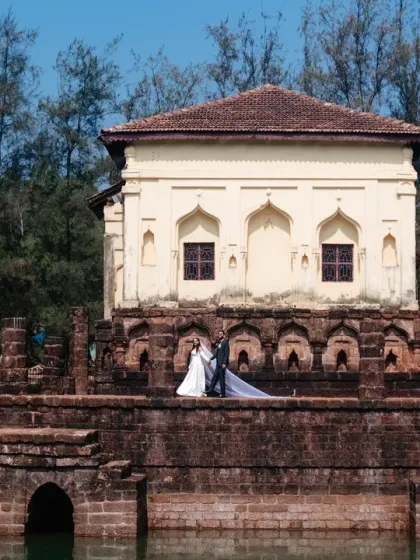 A wide shot from a Goa post-wedding session, featuring the couple against a historic Portuguese-style structure. This image showcases the unique architecture and serene beauty of a destination shoot in Goa.