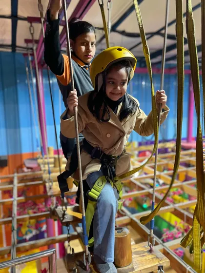 Our rope and bridge course offers a safe but exciting challenge. A staff member assists a young guest as she navigates the wooden planks.