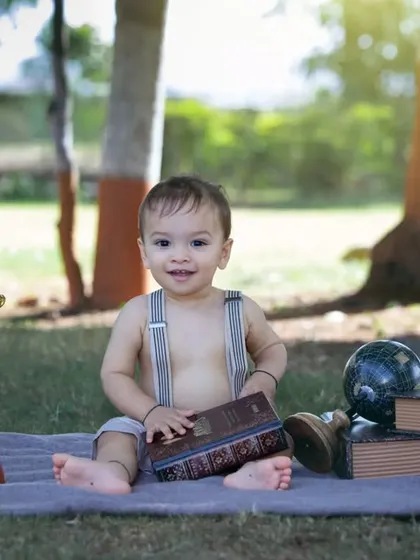 This happy little explorer is having fun with his books and telescope.