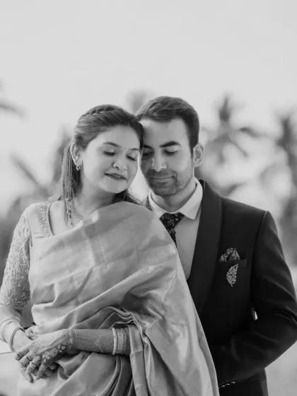 A timeless black and white portrait that exudes elegance. The focus is on their serene expressions and the beautiful texture of the saree, creating a classic and artistic image.