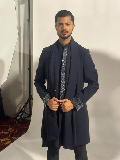 Posing for a photo against the studio backdrop backstage, showing the complete look from head to toe.