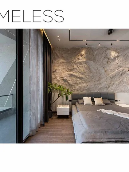 A timeless bedroom design with a textured rock-face wall, creating a raw, natural focal point. The large glass window provides a view of the building's angular facade.