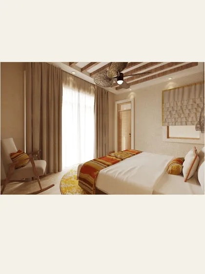 The bedroom design for Dev Villas, Kanha. The room features earthy tones, a comfortable rocking chair, and large windows with sheer curtains to let in soft, natural light.